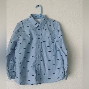 boy's shirt, sky blue, with navy blue shark pattern.